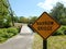 Yellow narrow bridge sign and asphalt trail and bridge