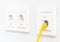 Yellow network cable in wall outlet for office or private home lan ethernet connection with power outlets flat view on white