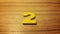 Yellow number 2 on wooden background
