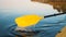 Yellow oar paddles in blue lake on kayak at sunset close-up, secluded vacation