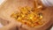 Yellow Omega 3 capsules falling into a cracked wooden bowl from a white pharmaceutical plastic bottle