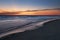 Yellow, orange and blue colors in twilight after sunset illuminate the sky and shiny, silky water along Barefoot Beach, Florida