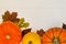 Yellow and orange pumpkins and autumn leaves on white wooden background for harvest fall and thanksgiving theme.