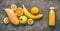 Yellow organic fruits smoothie with lemon, oranges, apple, mango and banana in bottle on gray granite table , top view.