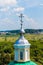 Yellow Orthodox Christian church with a green dome in summer against a blue sky with white clouds