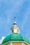 Yellow Orthodox Christian church with a green dome in summer against a blue sky with white clouds