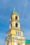 Yellow Orthodox Christian church with a green dome in summer against a blue sky with white clouds