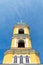 Yellow Orthodox Christian church with a green dome in summer against a blue sky with white clouds