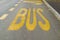 Yellow painted road sign that warns drivers that there is a bus stop