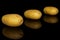 Yellow pale potato isolated on black glass