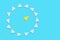 A yellow paper airplane flies through a circle of white planes. Blue background. It was flat. The concept of creativity and