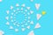 A yellow paper airplane flies out of the circle of white planes. Blue background. Flat lay. The concept of creativity and