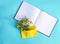 Yellow paper envelope with small garden white chamomile flowers and empty notepad on light blue background. Festive floral templat