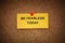 A yellow paper note with the phrase Be Fearless Today on it pinned to cork board