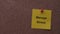 A yellow paper note with the words Manage Stress on it pinned to a cork board