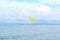 Yellow parachute in the blue sky over the sea on the island of Corfu, Greece. Parasailing extreme sports on the beach.