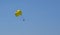 Yellow parachute in the blue sky over the sea. Parasailing extreme sports on the beach.