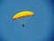 Yellow paraglider on blue sky.