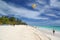 Yellow Paraglider hangs over sunbathers on white Caribbean beach