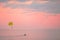 Yellow parasail wing pulled by a boat on beautiful pink sunset