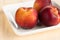 Yellow peaches on white square plate