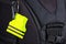 Yellow pedestrain safety reflector on a black backpack, closeup