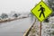 Yellow pedestrian crosswalk crossing street sign in winter snow