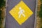 Yellow pedestrian priority sign on asphalt footpath