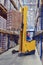 Yellow pedestrian stacker lifts pallet with boxes on the shelves