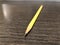 Yellow pencil with pointed granite pointing outwards lying on black patterned office desk