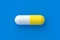 Yellow pill on blue background. Concept of healthcare and medical