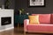 Yellow pillow on a powder pink, velvet sofa and a black, eco burning fireplace in a modern vintage living room interior