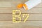 Yellow pills forming shape to B7 alphabet on wood background