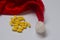 Yellow pills. Homeopathy, treatment, medicine. Pills, capsules. Christmas, decorations, santa claus hat. Drugs, virus, quarantine.