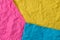 Yellow, pink and blue crumpled paper texture as background