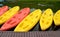 Yellow and pink canoes/kayaks in a row on waterside.