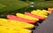 Yellow and pink canoes/kayaks in a row on waterside.