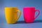Yellow and pink mugs isolated on blue background