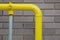 Yellow pipe against a brick wall