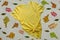 Yellow plain t-shirt mockup colorful autumn leaves gray background. Blank cotton shirt template