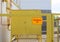 A yellow plaque that reads `Fire Gas` on a fence made of metal mesh enclosing gas equipment. The concept of gas supply, security