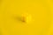 Yellow plastic building block on yellow background. Background of plastic detail building block. Part of bright small spare part