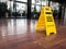 Yellow plastic cone with sign showing warning of wet floor in restaurant.