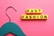Yellow plastic cubes with phrase Fast Fashion and hanger on pink background, flat lay
