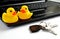 Yellow plastic ducks sit on notebook computer next to keys to house