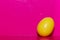 Yellow plastic egg in bottom right corner of a deep bright pink background. Open space. Concept