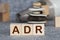 Yellow plastic forklift hold letter A to complete word ADR Abbreviation of Adverse drug reaction on wood background