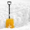 Yellow plastic shovel stuck in fluffy white snow in winter