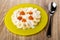 Yellow plate with defatted cottage cheese, slices of banana, jam and yogurt, spoon on table
