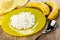 Yellow plate with grainy cottage cheese, napkin, bananas, spoon on wooden table